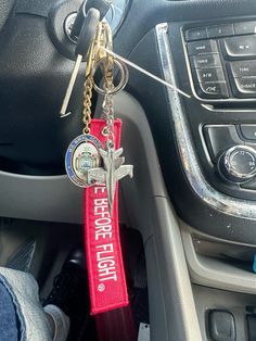 a red keychain hanging from the center console of a car with a cross on it