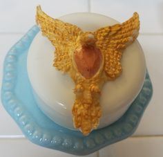 a small candle with a bird decoration on it's top sitting on a blue and white plate