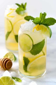 two glasses filled with lemonade, lime and mint