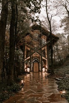 a wooden structure in the middle of a forest surrounded by trees and rocks with lights on it