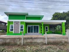 a green and white house sitting on top of a dirt field