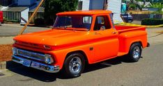 an orange pickup truck parked in front of a house