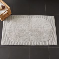 a white rug on the floor with a basket next to it