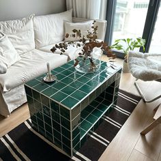 a living room with a white couch and green tiled coffee table