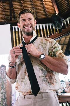 a man is smiling while tying his tie