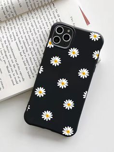 a black phone case with white daisies on it and an open book in the background