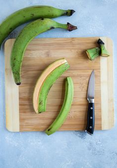 a cutting board with some bananas on it and a knife in the middle next to them