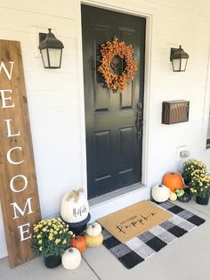 a welcome sign on the front door of a house with pumpkins and gourds