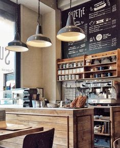 the interior of a coffee shop with wooden tables and hanging lights over it's counter