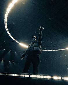 a man standing on top of a stage with his arms in the air and lights behind him