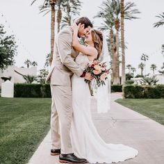 a bride and groom kissing in front of palm trees