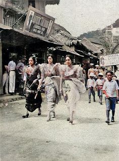 an old black and white photo of people walking down the street in front of shops