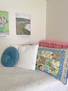 a bed with two pillows on top of it and three pictures above the headboard