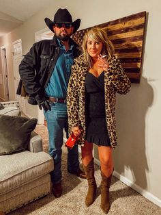 a man and woman in cowboy hats standing next to each other, posing for the camera