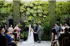 a bride and groom standing at the end of their wedding ceremony in front of a green wall