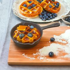 blueberries and waffles are being cooked in a pan on a cutting board