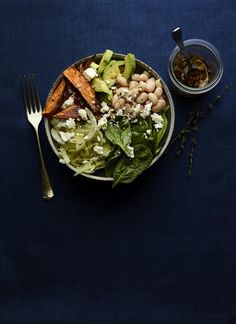 a salad with beans, lettuce and carrots in a bowl next to a fork