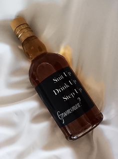 a bottle of wine sitting on top of a white bed sheet with the label saying, what do you drink?