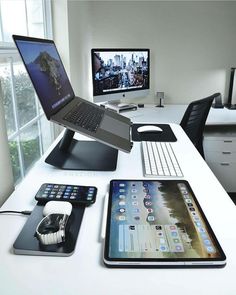 an office desk with two computers on it and various accessories sitting on top of it