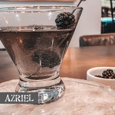 a glass filled with blackberries sitting on top of a table