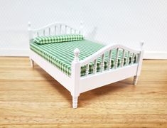 a dollhouse bed with green and white checkered bedspread on the bottom