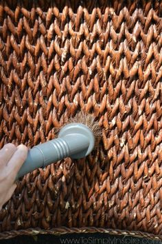 a person is using a brush to clean a woven piece of material with a plastic handle