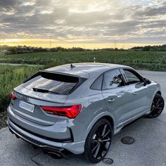 an audi suv parked in front of a corn field at sunset with the sun shining on it