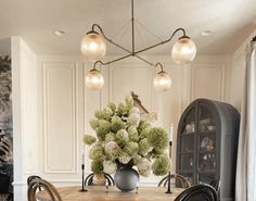 a dining room table with chairs and a vase filled with flowers on top of it