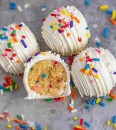 white cake truffles with sprinkles are on a gray surface surrounded by confetti