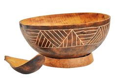 an old wooden bowl with designs on it and a piece of wood in the foreground