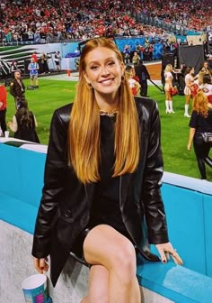 a woman sitting in the stands at a baseball game with her legs crossed and feet up