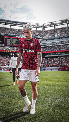 a soccer player is walking on the field in front of an empty stadium full of people