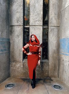 a woman in a red dress and black boots poses for the camera with her hands on her hips