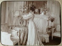 an old fashion photo of a woman standing in front of a table with flowers on it