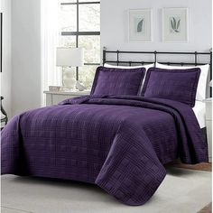 a bed with purple bedspread and pillows