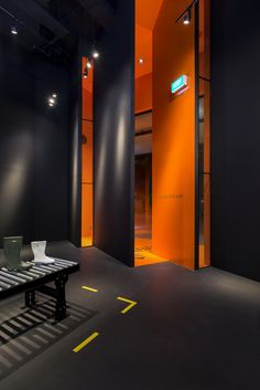 an empty bench sits in the middle of a room with orange walls and black flooring