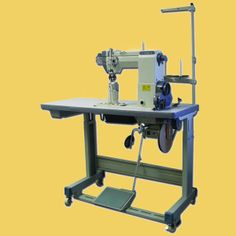 an industrial sewing machine with wheels and foot pedals sitting on a yellow background in front of the camera