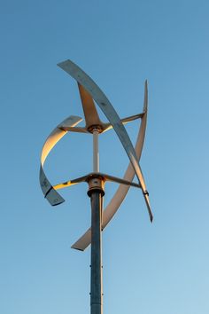 a large metal sculpture on top of a pole with blue sky in the back ground