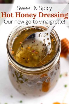 a jar filled with honey dressing on top of a white plate next to a spoon