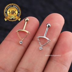 two different piercings are shown on someone's finger, one is gold and the other is silver