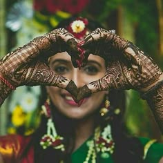 a woman making a heart shape with her hands while wearing hennap and jewelry