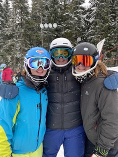 three skiers posing for a photo in the snow