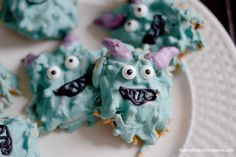 cookies decorated with blue icing and googly eyes are on a white platter