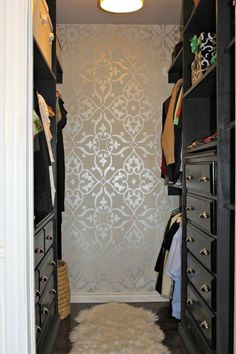 an open closet with drawers and clothes hanging on the wall, next to a rug