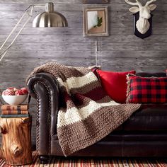 a living room with a leather couch, plaid blanket and deer head on the wall