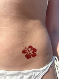 a woman's stomach with a red flower tattoo on it