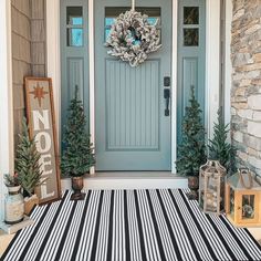 a front porch decorated for christmas with black and white striped rug, wreaths and decorations