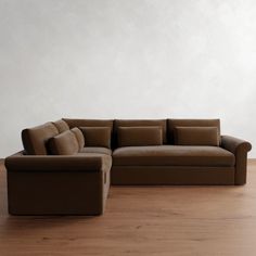 a brown couch sitting on top of a hard wood floor next to a white wall