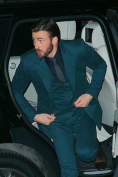 a man in a green suit is stepping out of a car with his hands on his hips