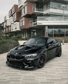 a black bmw car parked in front of a large building with balconies on it